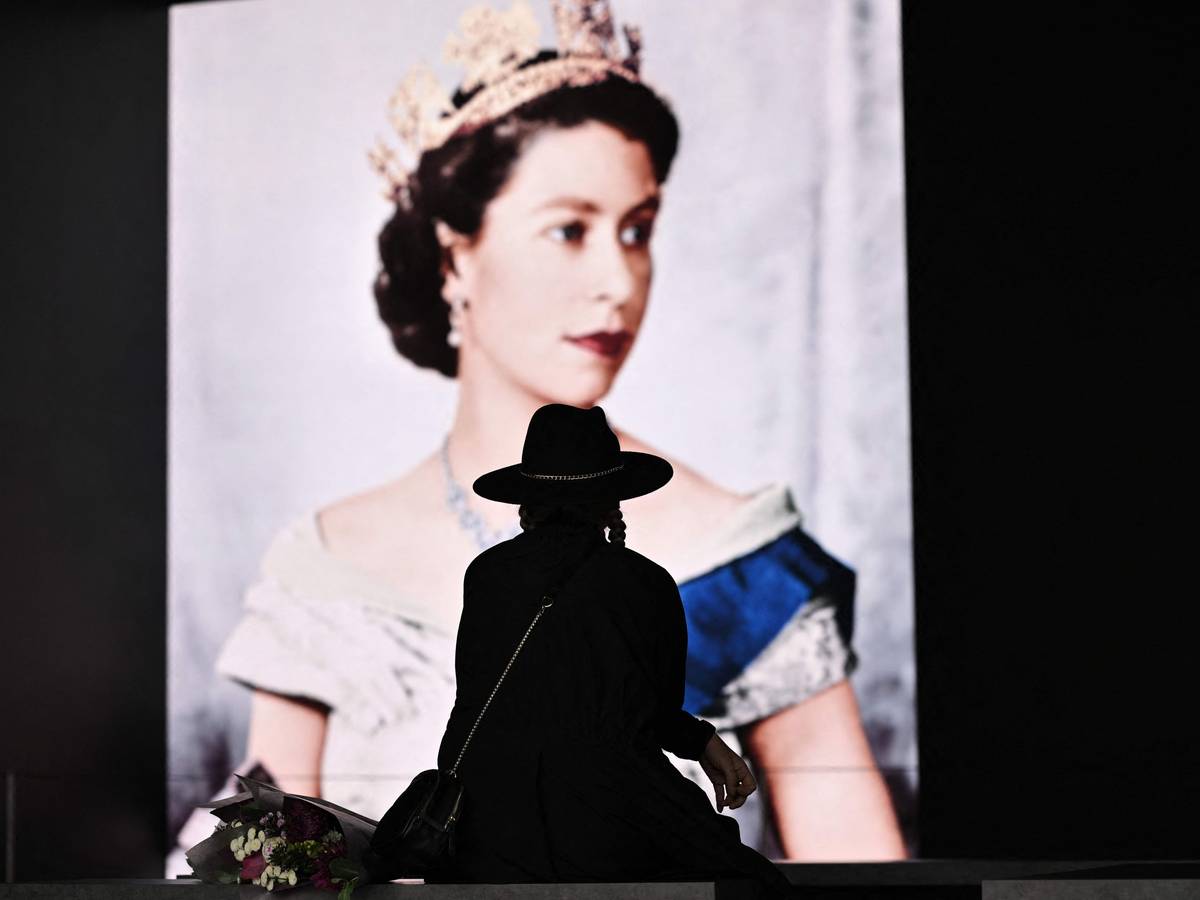 Trauer um die Queen in London: Eine Britin legt am Samstag (10. September) Blumen vor dem Konterfei Elizabeth II. ab.
