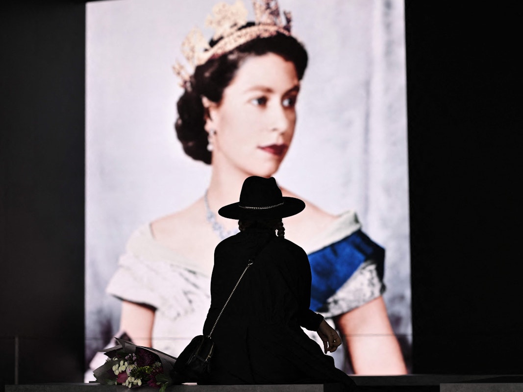 Trauer um die Queen in London: Eine Britin legt am Samstag (10. September) Blumen vor dem Konterfei Elizabeth II. ab.