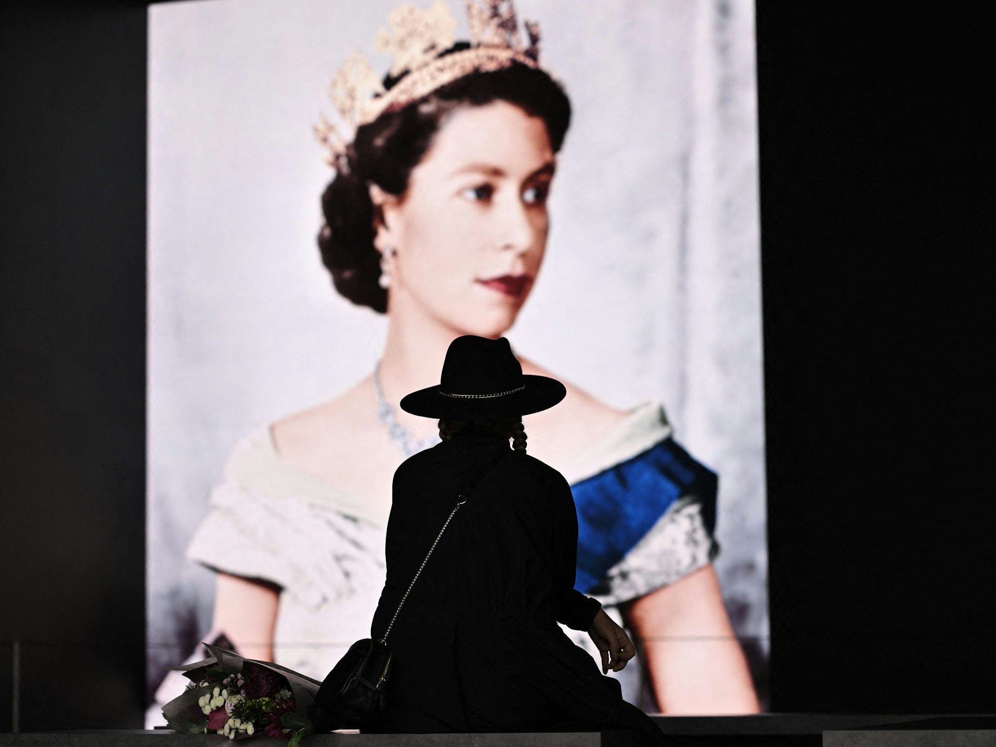 Trauer um die Queen in London: Eine Britin legt am Samstag (10. September) Blumen vor dem Konterfei Elizabeth II. ab.