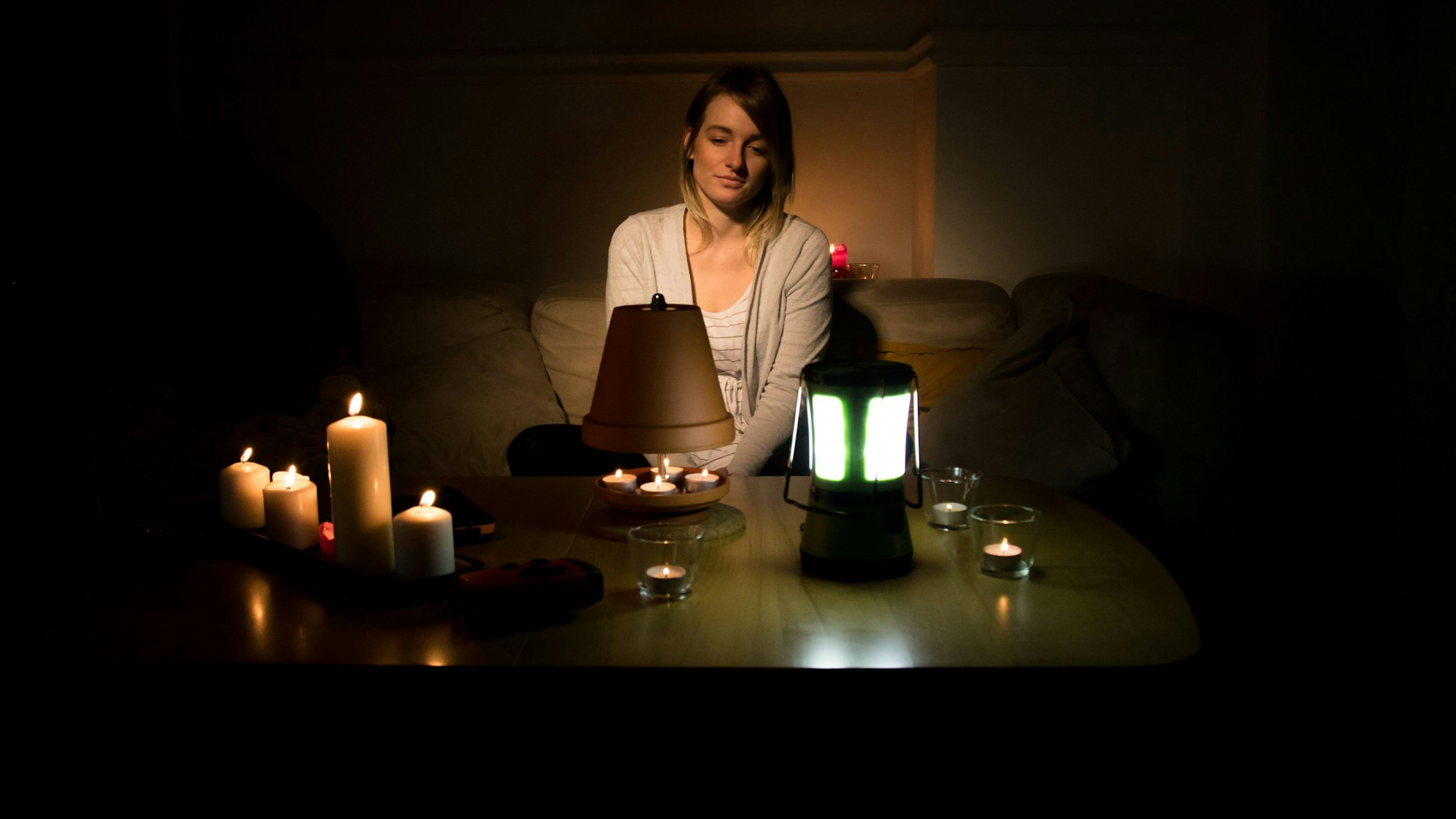 Der Deutsche Städte- und Gemeindebund fürchtet eine Überlastung des Stromnetzes. Auf einen Blackout sei Deutschland jedoch zu wenig vorbereitet. Unser Symbolbild zeigt eine Frau vor Kerzen und Teelichtern.