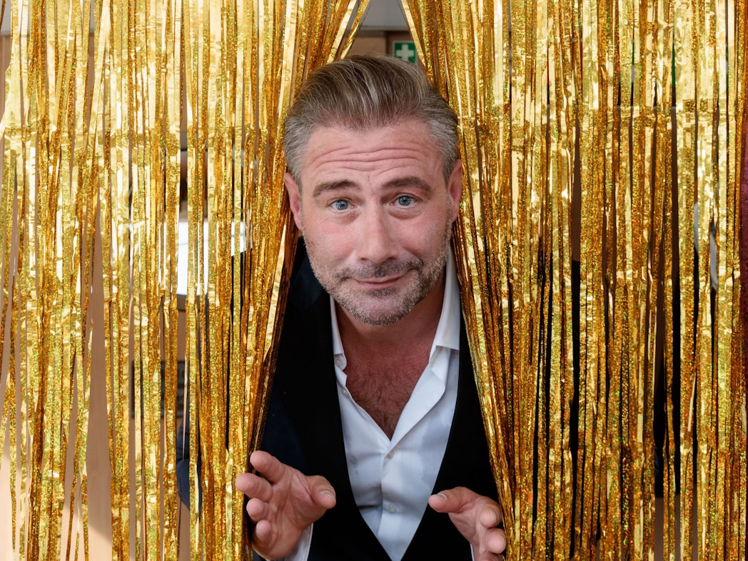 Der Sänger und Entertainer Sasha sieht auf einem Pressetermin zur Vorstellung seiner Show "This Is My Time - Die Show" durch einen goldenen Lametta-Vorhang.