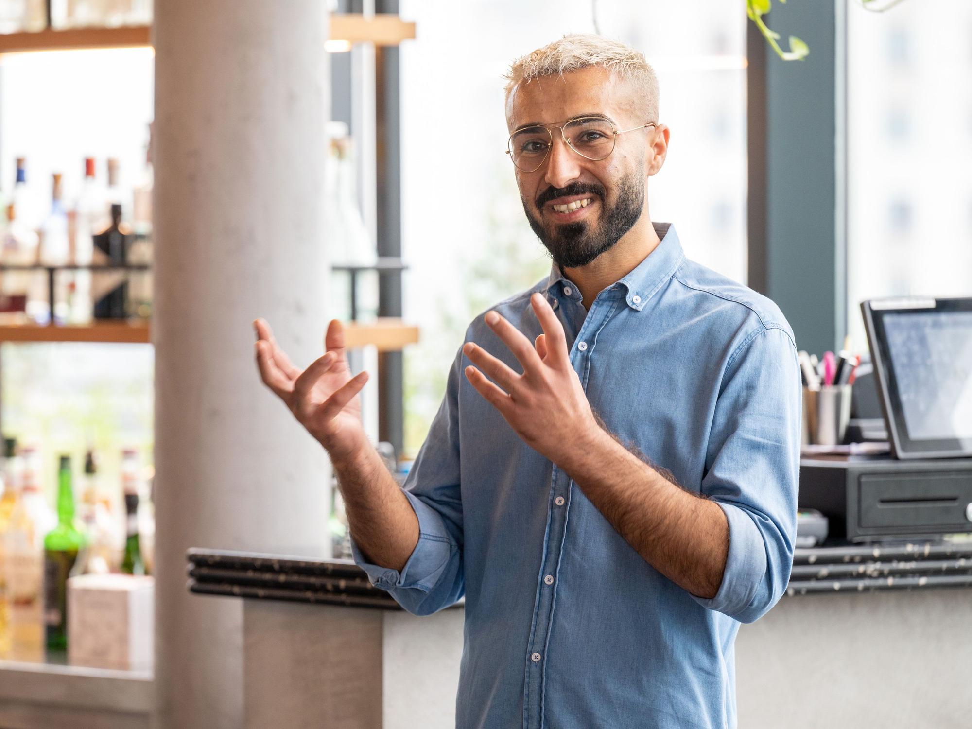 Der Manager der Bar „Botanik“, Ehsan Kasem, steht in seiner Lokalität und gestikuliert.