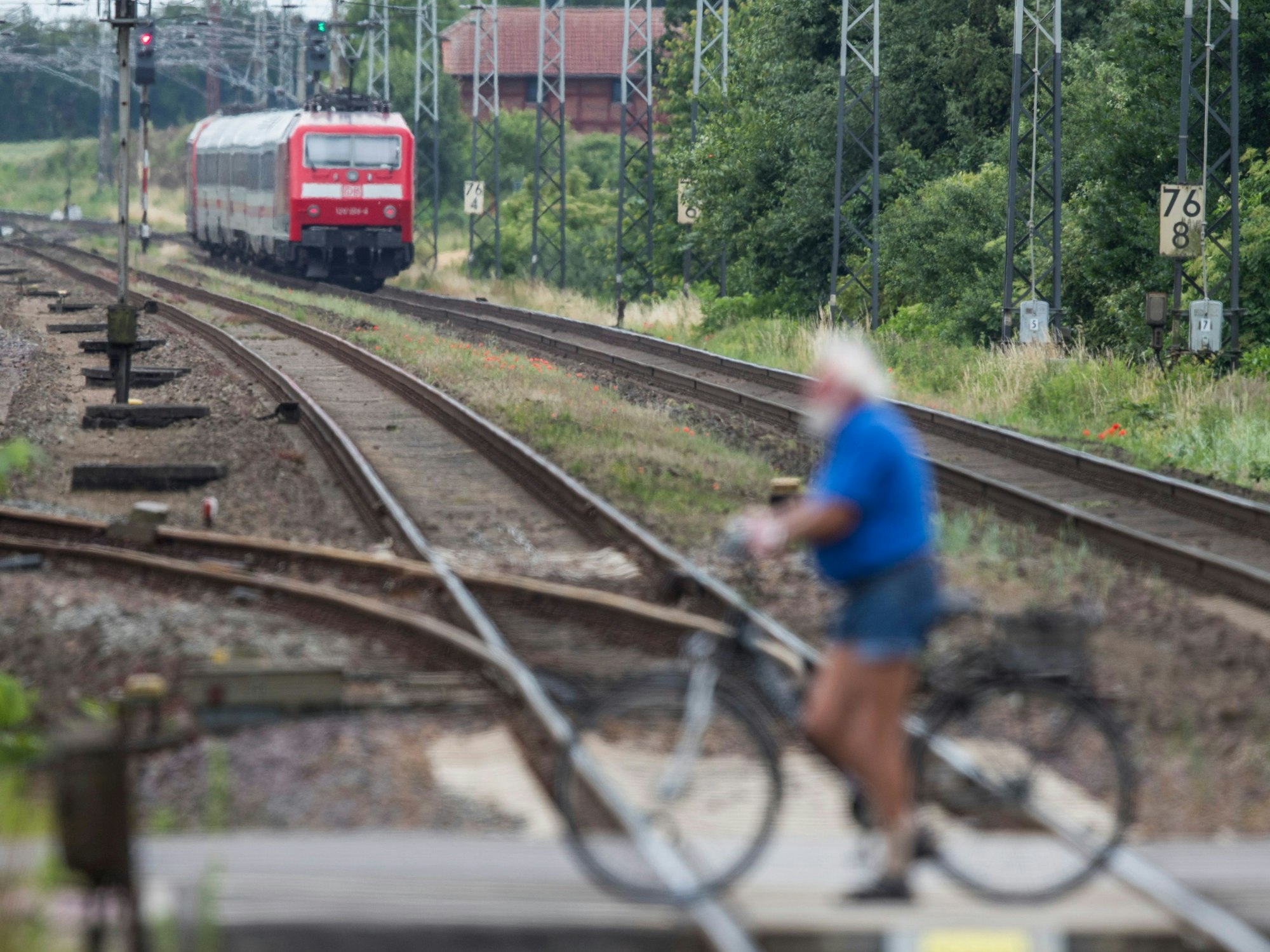 Ein Mann schiebt sein Fahrrad über einen Bahnübergang.