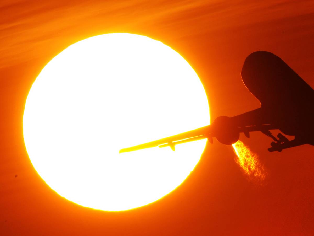 Ein Flugzeug startet am 08. Februar 2011 vom Düsseldorfer Flughafen vor der Kulisse eines spektakulären Sonnenuntergangs.