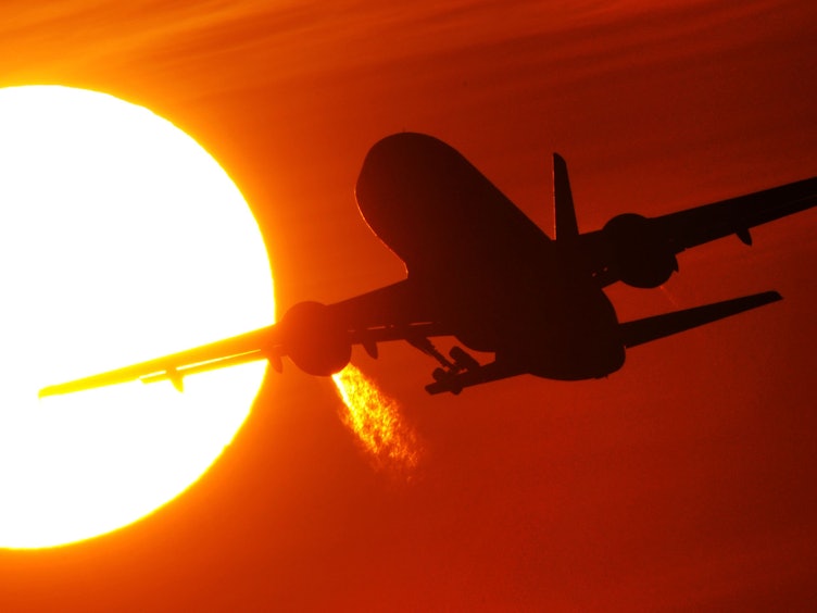 Ein Flugzeug startet am 08. Februar 2011 vom Düsseldorfer Flughafen vor der Kulisse eines spektakulären Sonnenuntergangs.