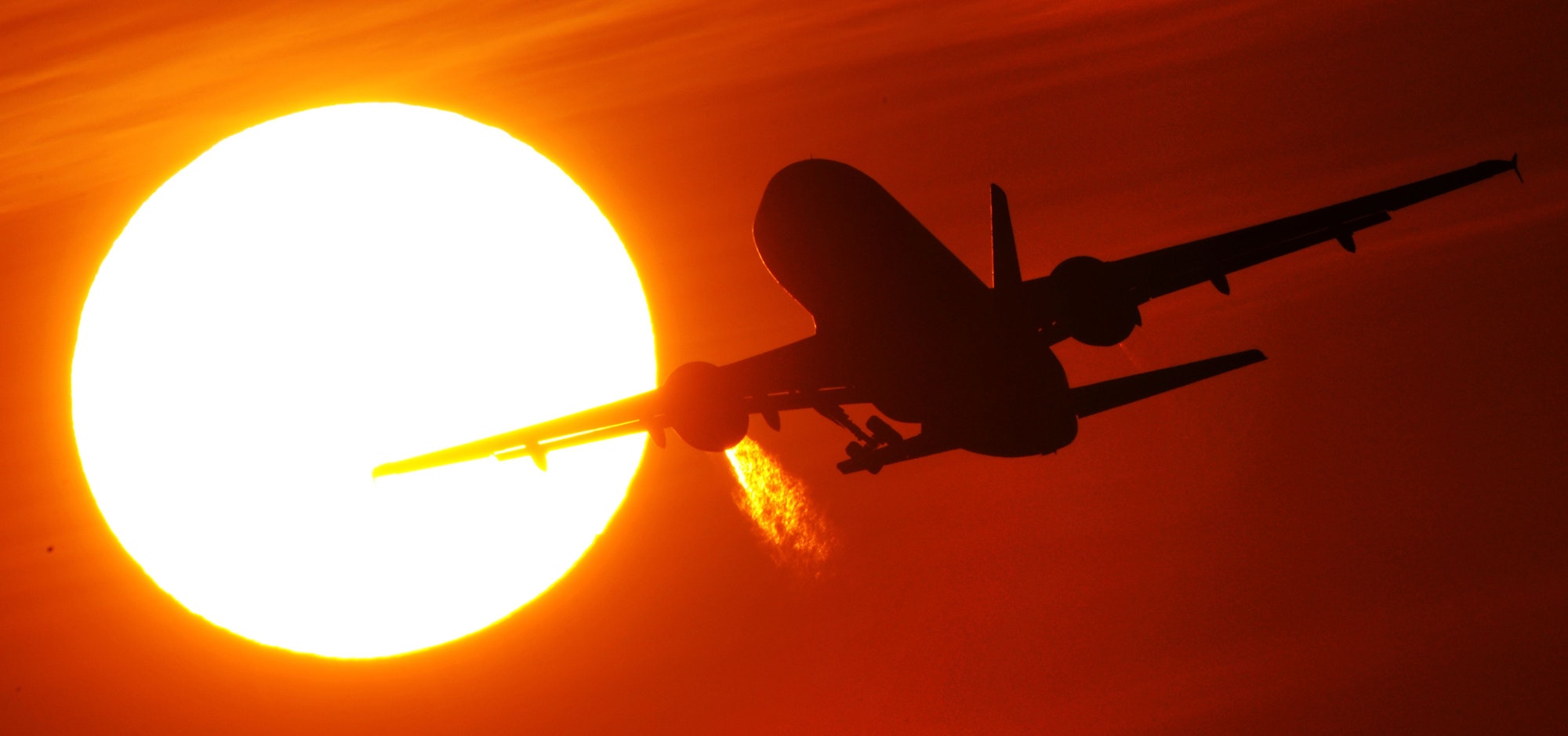 Ein Flugzeug startet am 08. Februar 2011 vom Düsseldorfer Flughafen vor der Kulisse eines spektakulären Sonnenuntergangs.