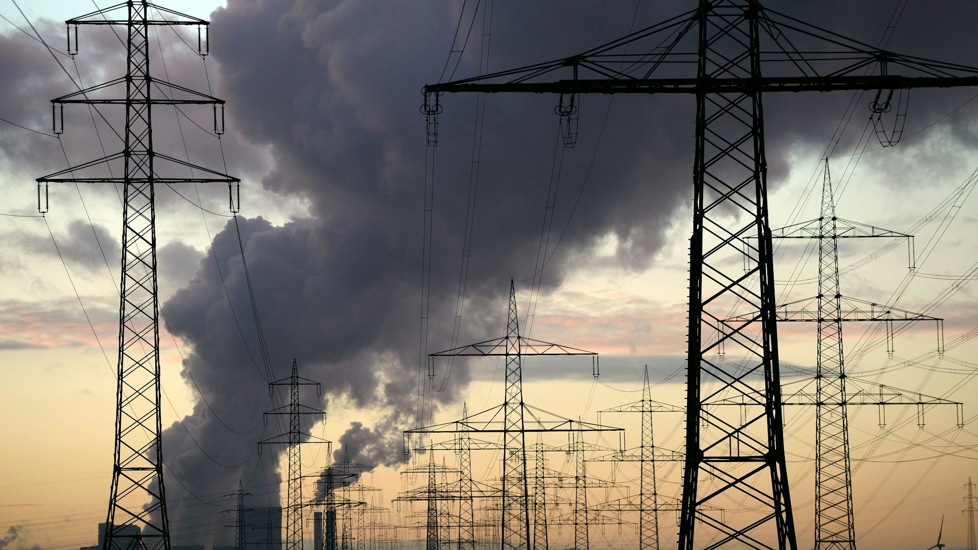 Strommasten sind bei Sonnenuntergang auf einem Feld bei Pulheim zu sehen.