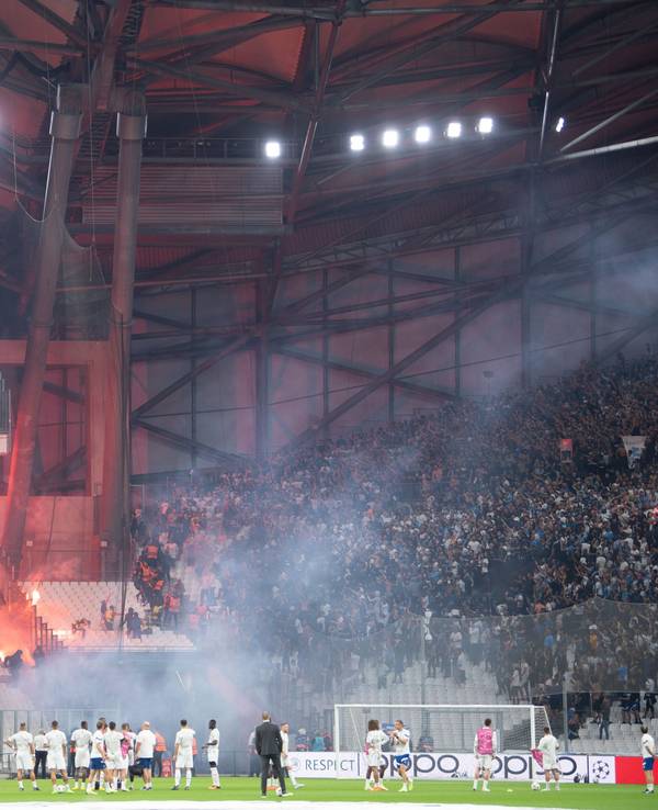 Die Blöcke der Ultras der Eintracht (l) und von Marseille beschießen sich mit Feuerwerk.