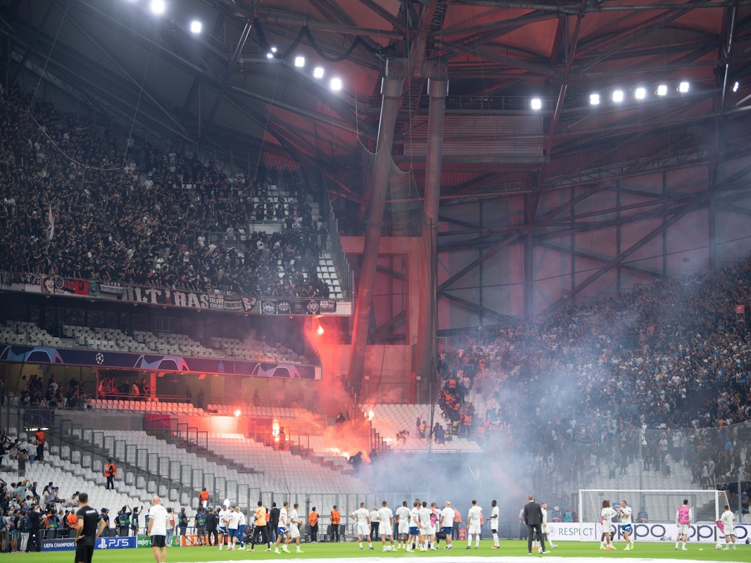 Die Blöcke der Ultras der Eintracht (l) und von Marseille beschießen sich mit Feuerwerk.