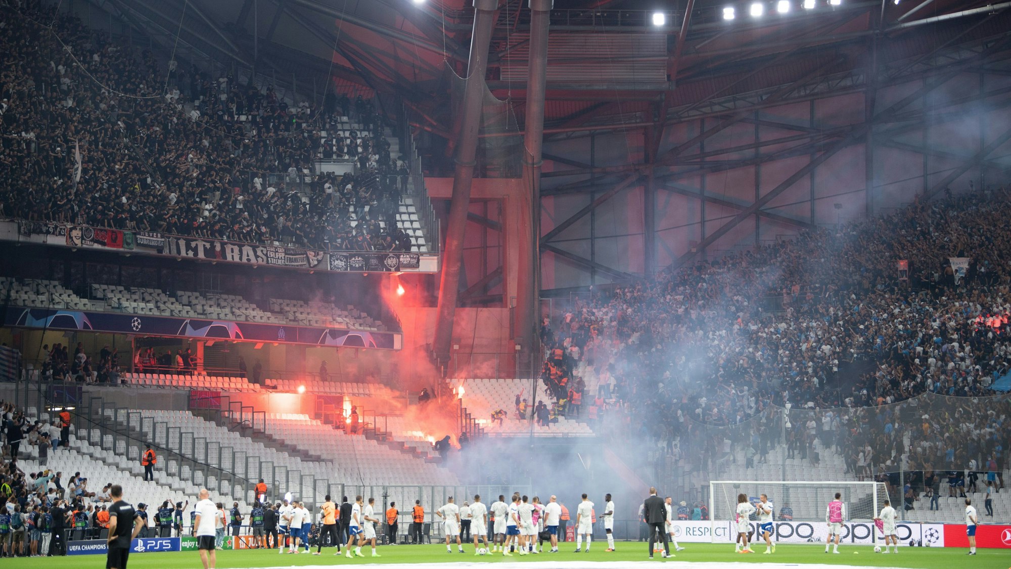 Die Blöcke der Ultras der Eintracht (l) und von Marseille beschießen sich mit Feuerwerk.