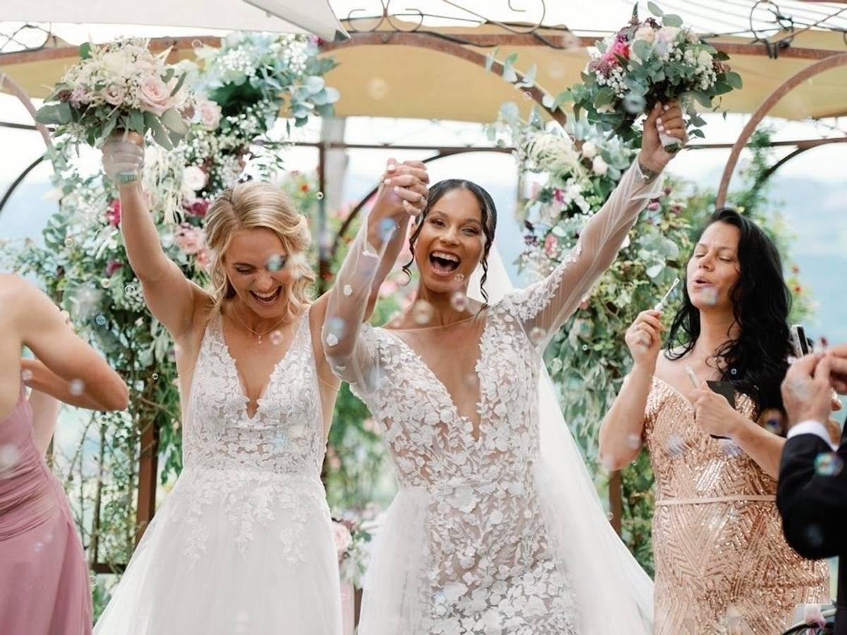 Sarah (l.) und Genessee Puntigam halten ihre Blumensträuße bei ihrer Hochzeit in die Höhe