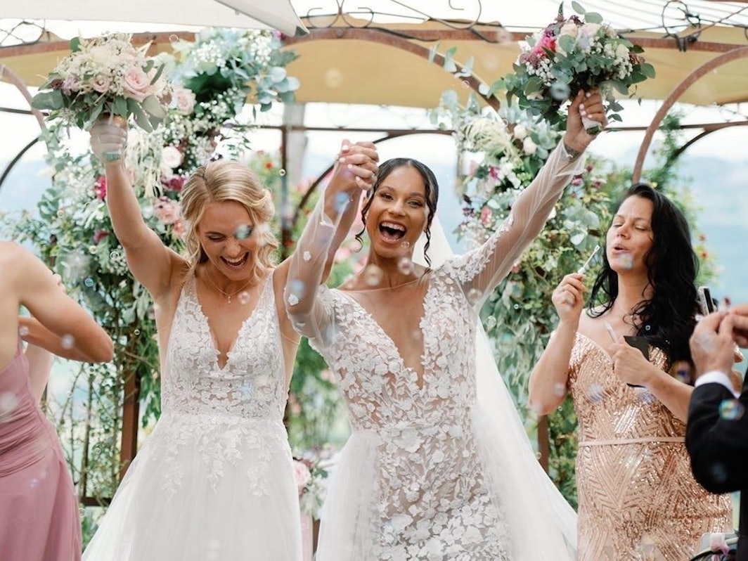 Sarah (l.) und Genessee Puntigam halten ihre Blumensträuße bei ihrer Hochzeit in die Höhe