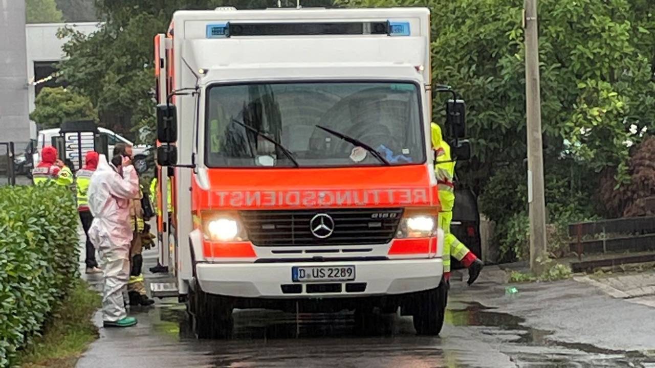 Einsatzkräfte in Schutzanzügen wuseln um einen Rettungswagen.