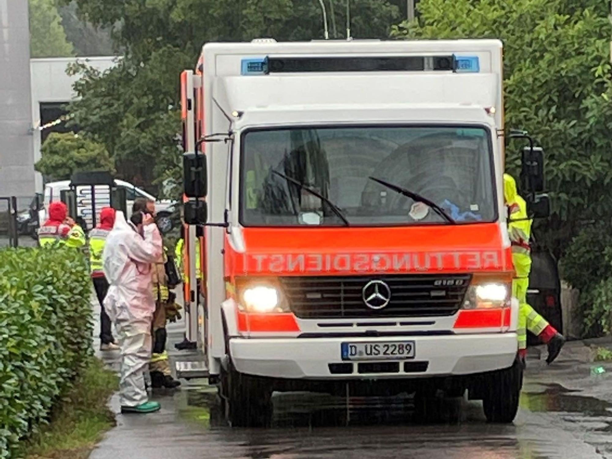 Einsatzkräfte in Schutzanzügen wuseln um einen Rettungswagen.