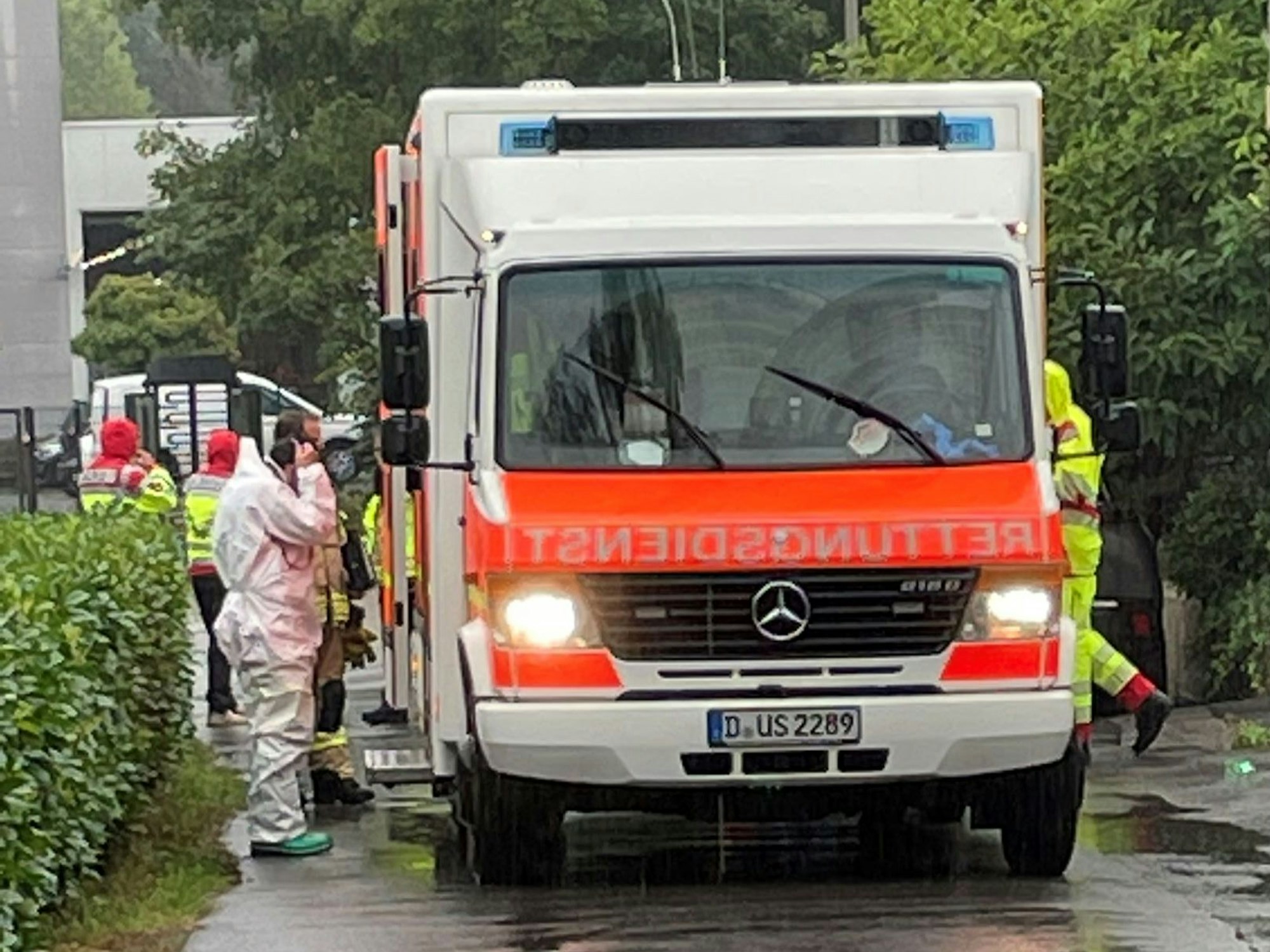 Einsatzkräfte in Schutzanzügen wuseln um einen Rettungswagen.