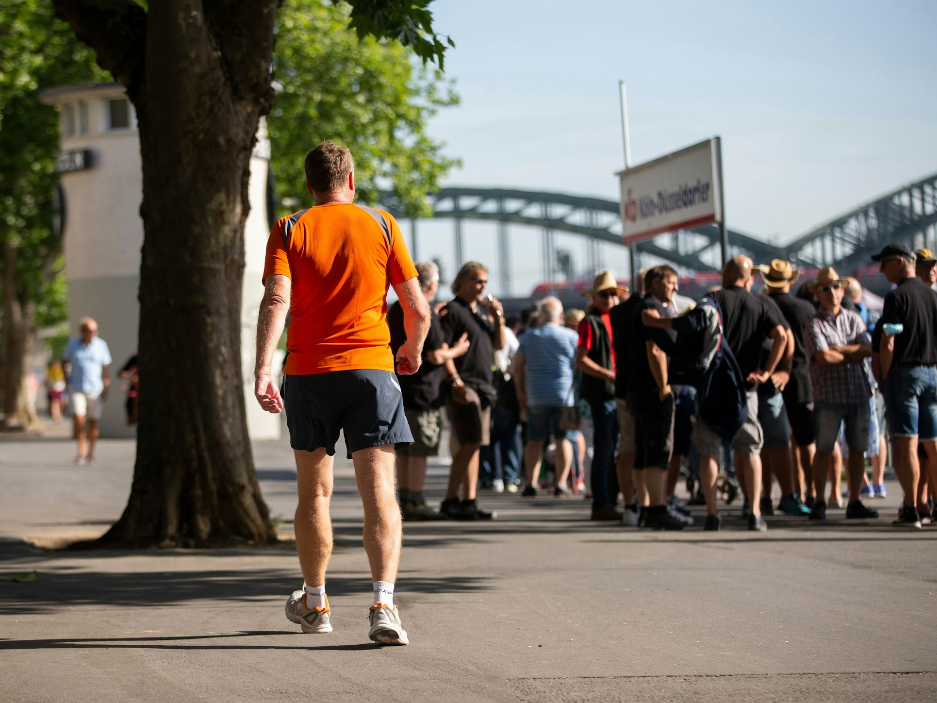 Touristinnen und Touristen stehen an der Kölner Rheinuferpromenade an, um mit einem Ausflugsschiff auf dem Rhein zu fahren.