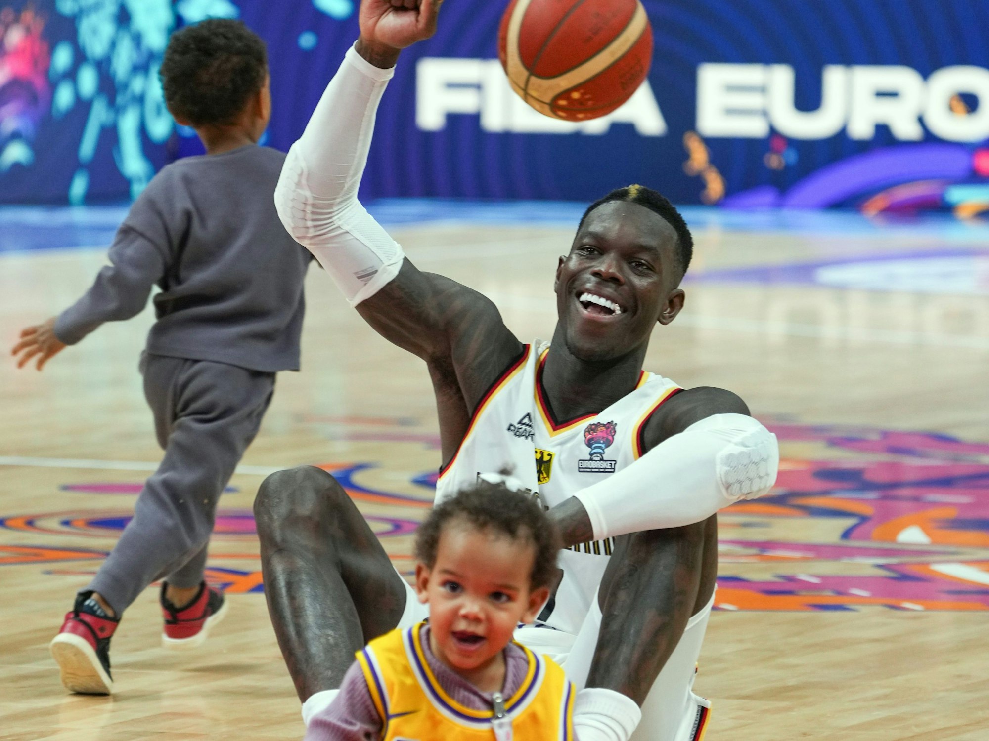 Dennis Schröder (Deutschland) sitzt nach dem Spiel mit seinen beiden Kindern auf dem Spielfeld.