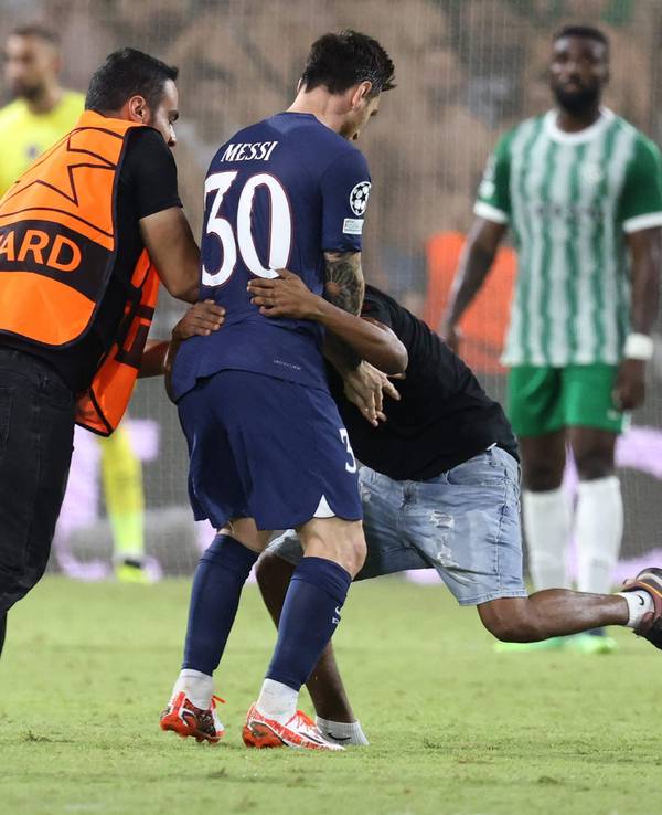 Ein Flitzer umarmt Lionel Messi während des Spiels von Paris St. Germain bei Maccabi Haifa. Ein Ordner versucht die beiden voneinander zu trennen.