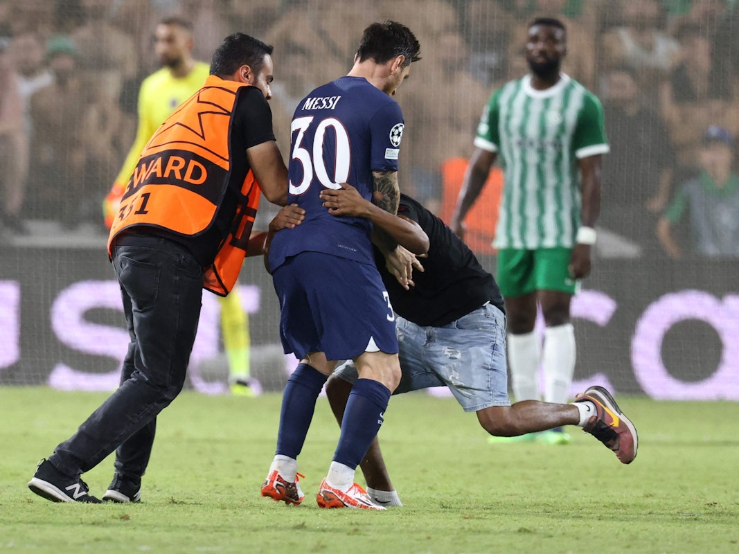 Ein Flitzer umarmt Lionel Messi während des Spiels von Paris St. Germain bei Maccabi Haifa. Ein Ordner versucht die beiden voneinander zu trennen.