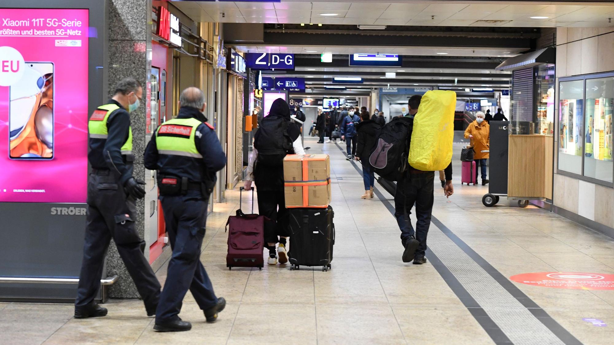Reisende und Sicherheitskräfte gehen im Hauptbahnhof durch einen Gang zu den Bahnsteigen.