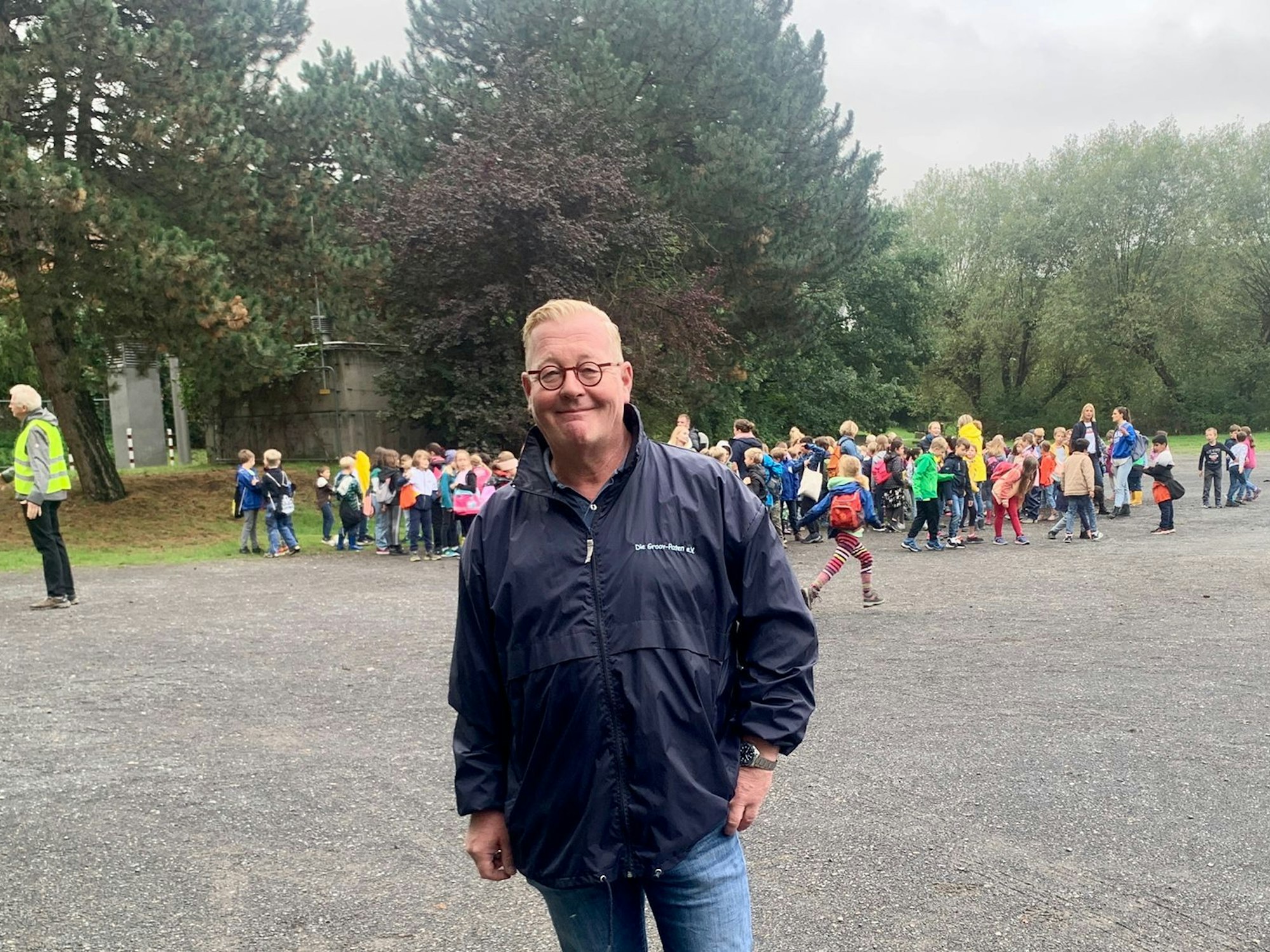 Andreas Bischoff lächelt vor den Grundschulkindern im Hintegrund in die Kamera.