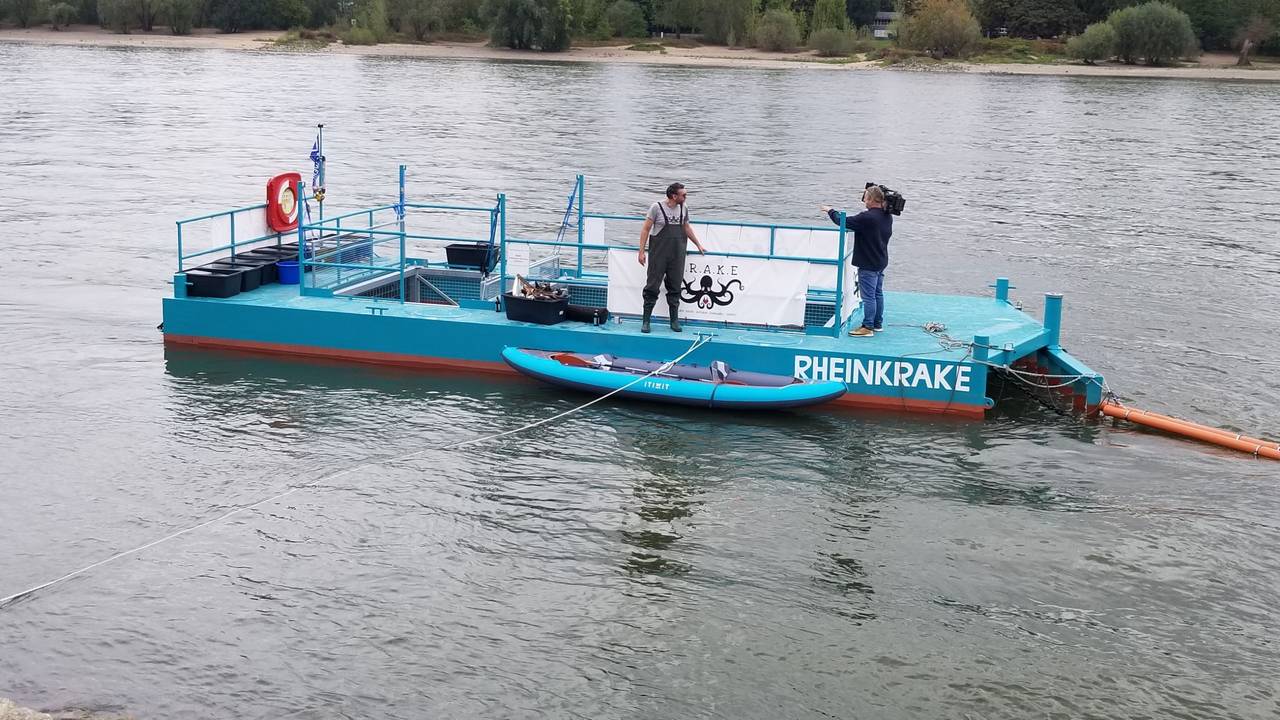 Ein blauer Ponton schwimmt auf dem Rhein bei Köln. Damit wird Müll aus dem Wasser gefischt.