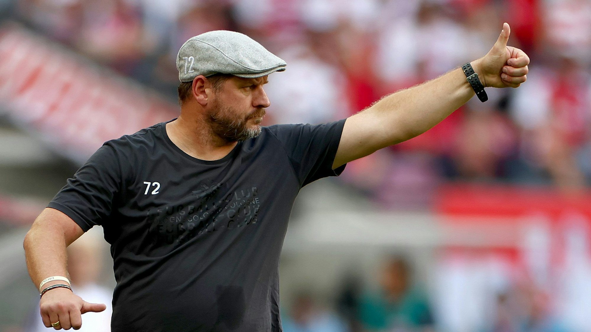 Steffen Baumgart, Trainer des 1. FC Köln, trägt eine Schiebermütze und hebt den Daumen nach oben