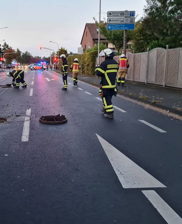 Einsatzkräfte der Feuerwehr Euskirchen begutachten die Lage am Rüdesheimer Ring. Gullydeckel liegen auf der Straße.
