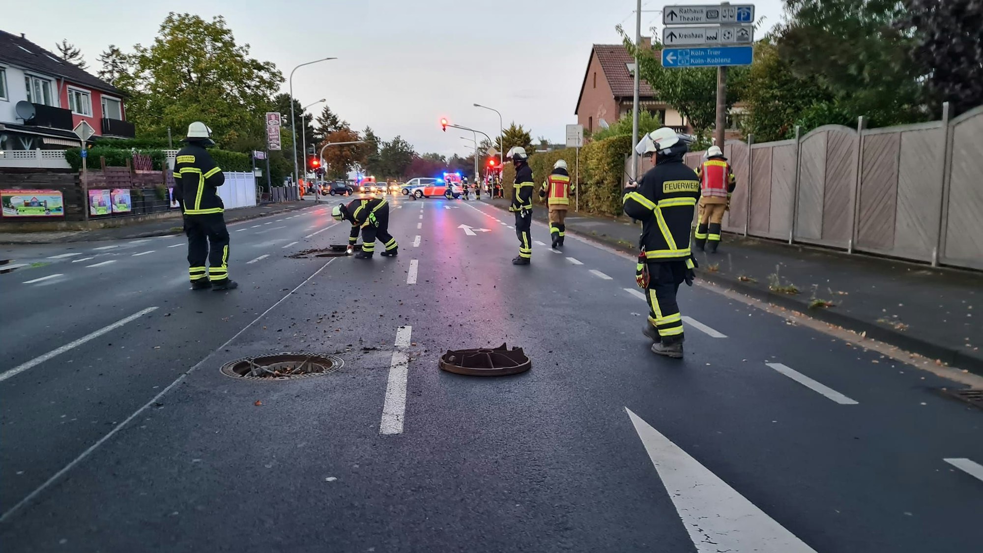 Einsatzkräfte der Feuerwehr Euskirchen begutachten die Lage am Rüdesheimer Ring. Gullydeckel liegen auf der Straße.