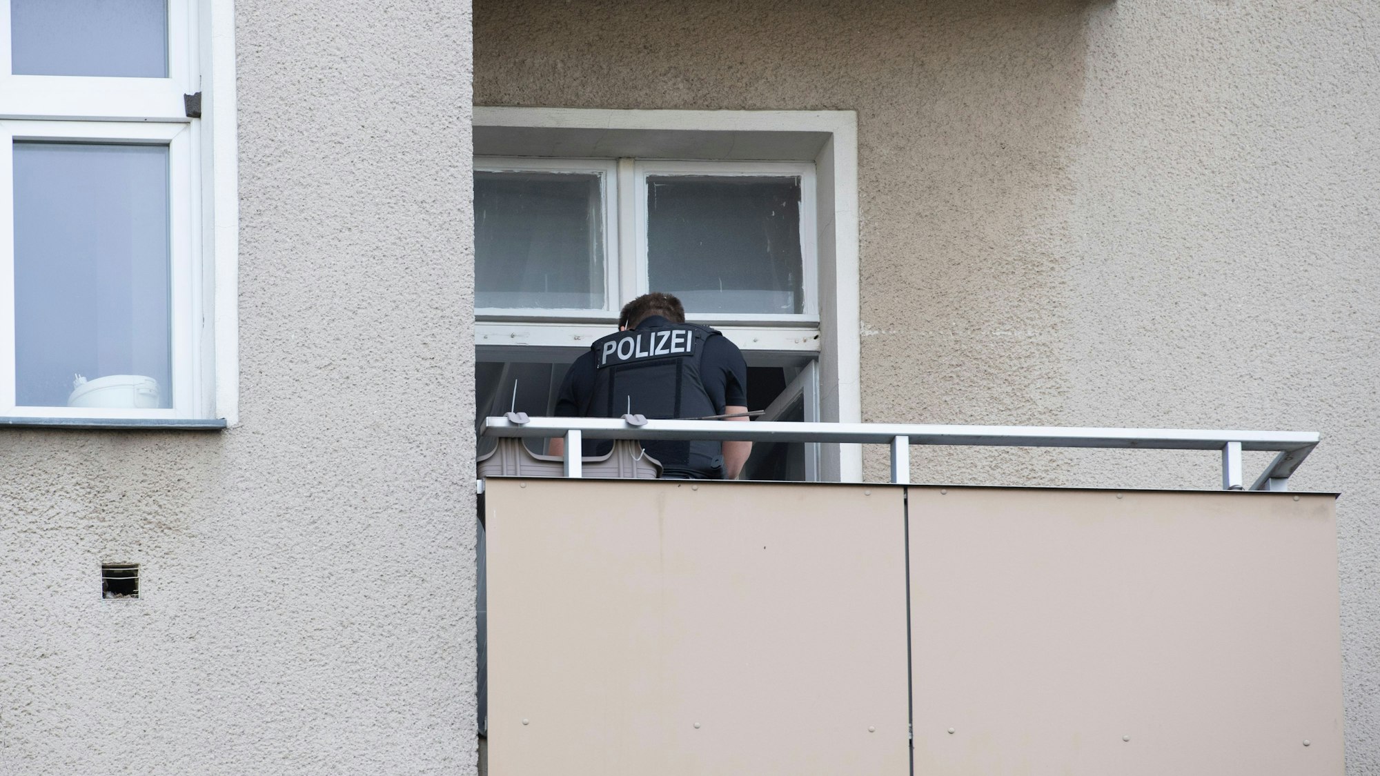 In unserem Symbolbild steht ein Polizist auf einem Balkon eines Berliner Wohnhauses. Der Polizeieinsatz bei einer syrischen Familie in Berlin geriet völlig aus dem Ruder, Videoaufnahmen davon machen in den sozialen Netzwerken die Runde.