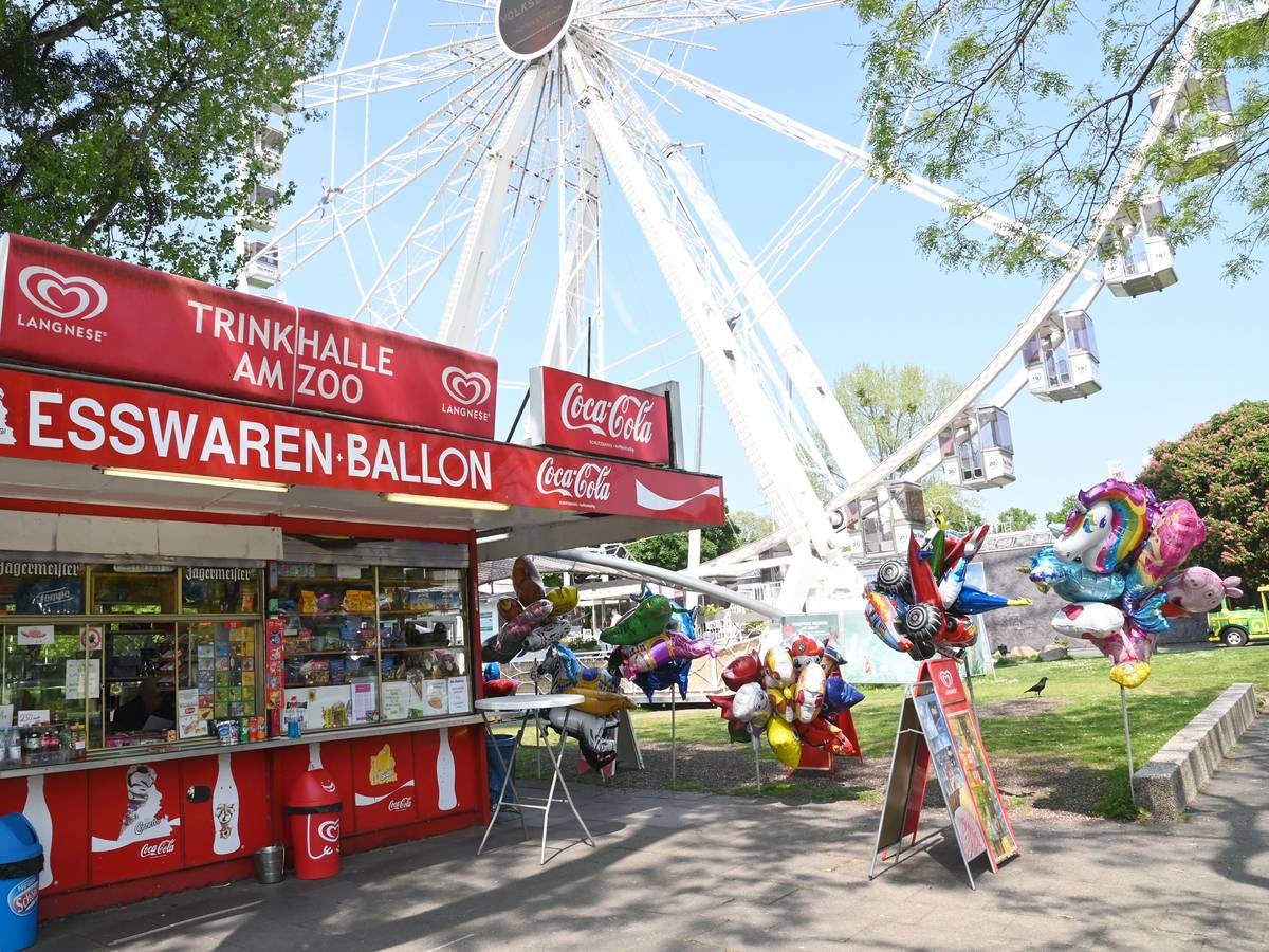 Büdchen mit Luftballons und Deko vor dem Riesenrad und dem Haupteingang des Kölner Zoos.