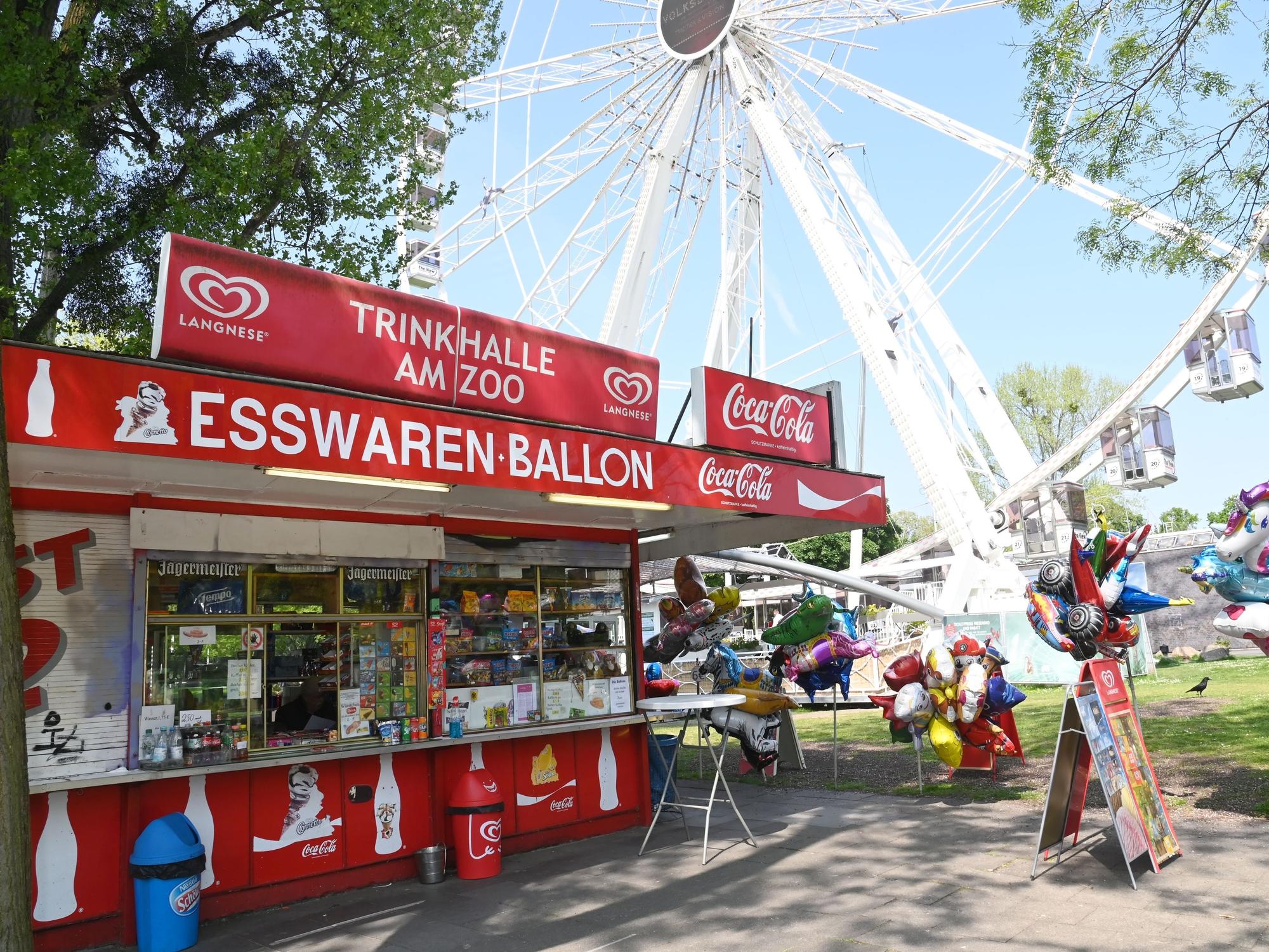 Büdchen mit Luftballons und Deko vor dem Riesenrad und dem Haupteingang des Kölner Zoos.