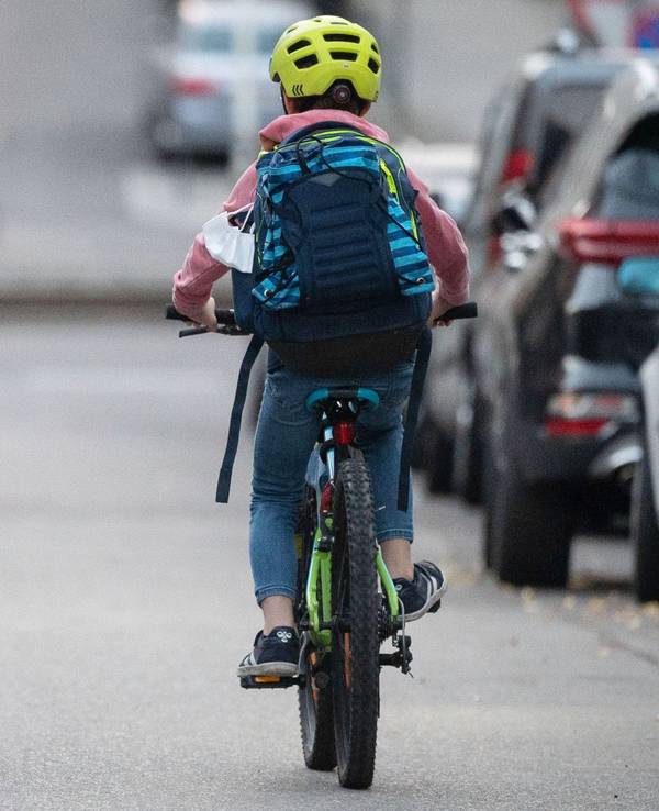 Ein Schulkind fährt mit seinem Fahrrad eine Straße entlang.