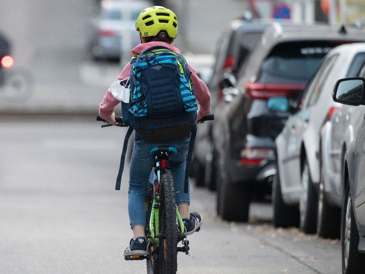 Ein Schulkind fährt mit seinem Fahrrad eine Straße entlang.