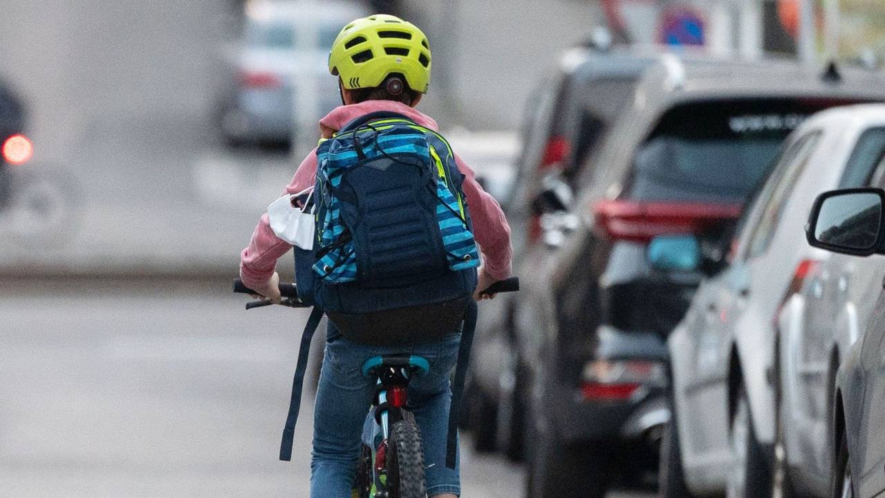 Ein Schulkind fährt mit seinem Fahrrad eine Straße entlang.