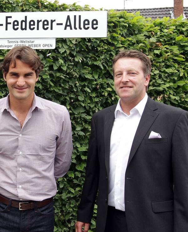 Anne Wesselmann, Roger Federer und Ralf Weber stehen vor dem Straßenschild zur „Roger-Federer-Allee“.