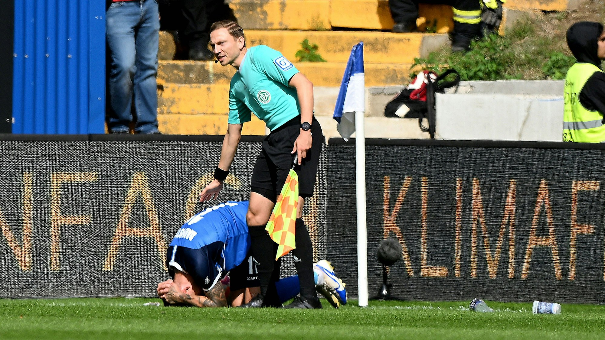 Tobias Kempe kauert am Boden, nachdem er von einem Bier-Becher am Kopf getroffen wurde.