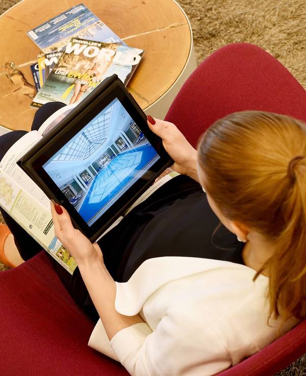 Eine Frau sitzt auf einem Sessel und schaut online nach den passenden Unterkünften für den Urlaub.