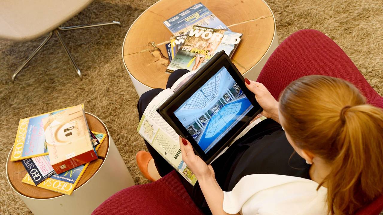 Eine Frau sitzt auf einem Sessel und schaut online nach den passenden Unterkünften für den Urlaub.
