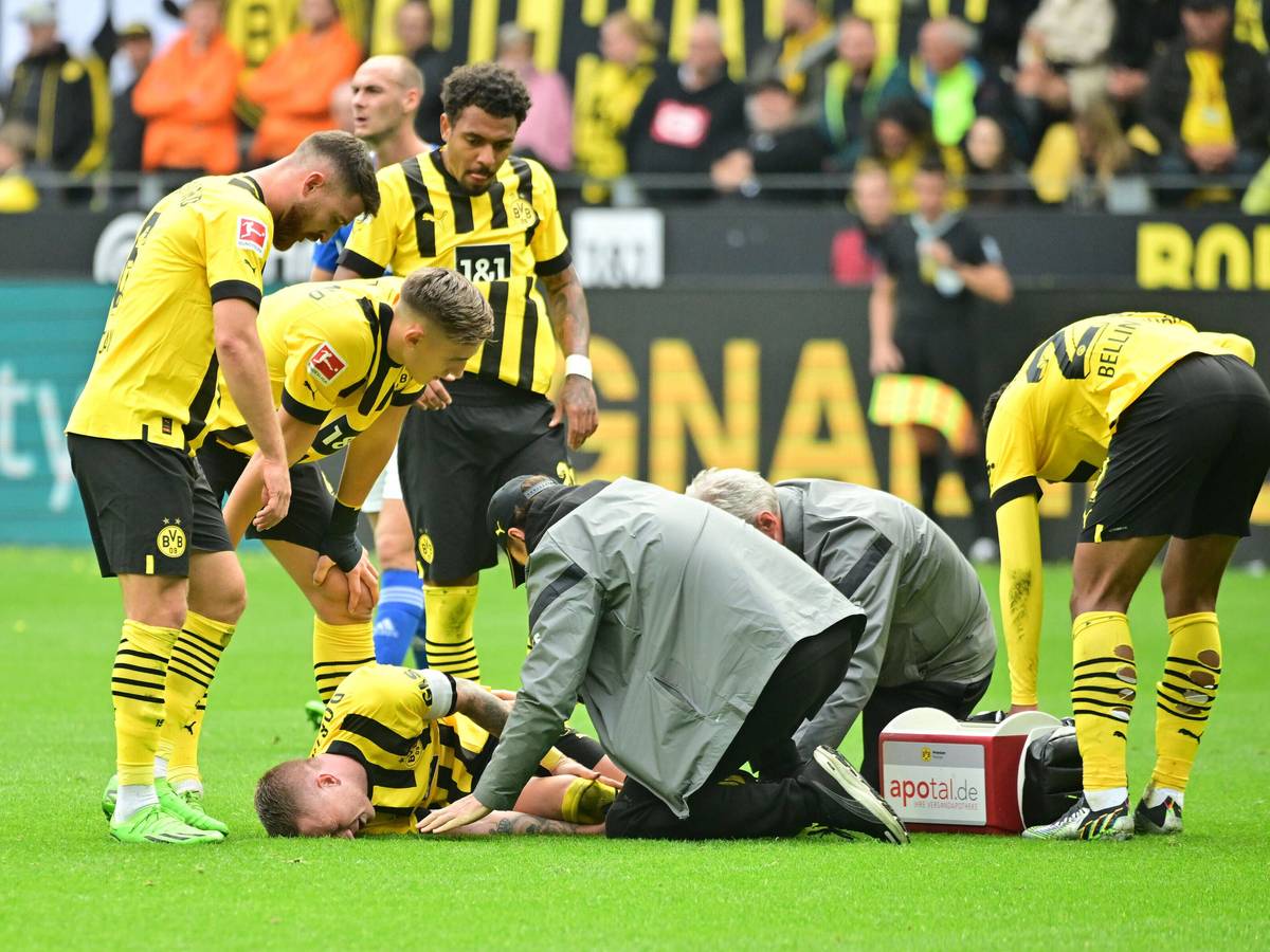 Marco Reus liegt auf dem Rasen und wird vom medizinischen Personal versorgt.