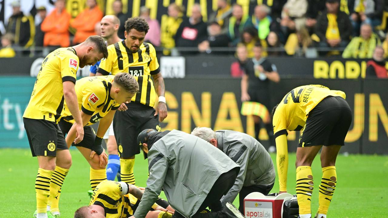 Marco Reus liegt auf dem Rasen und wird vom medizinischen Personal versorgt.