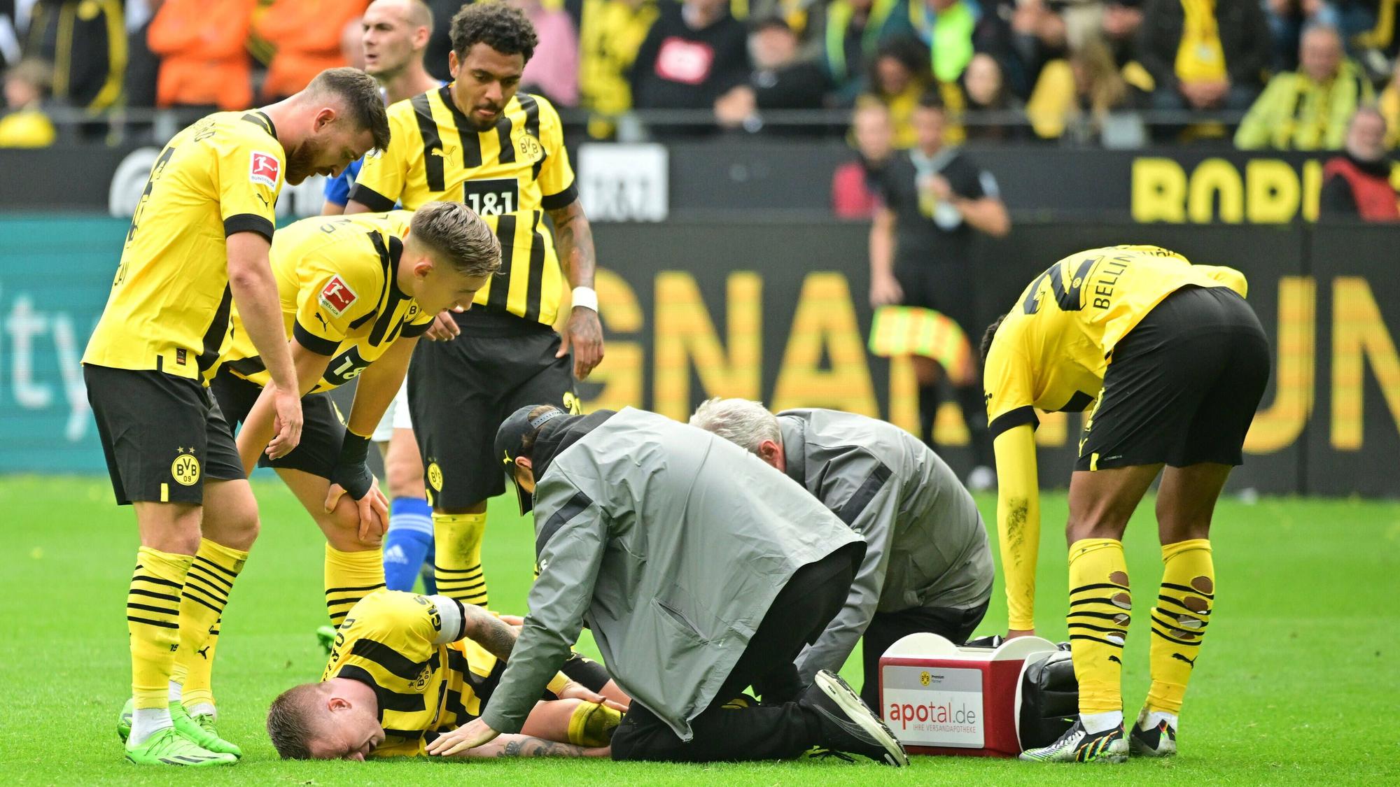 Marco Reus liegt auf dem Rasen und wird vom medizinischen Personal versorgt.