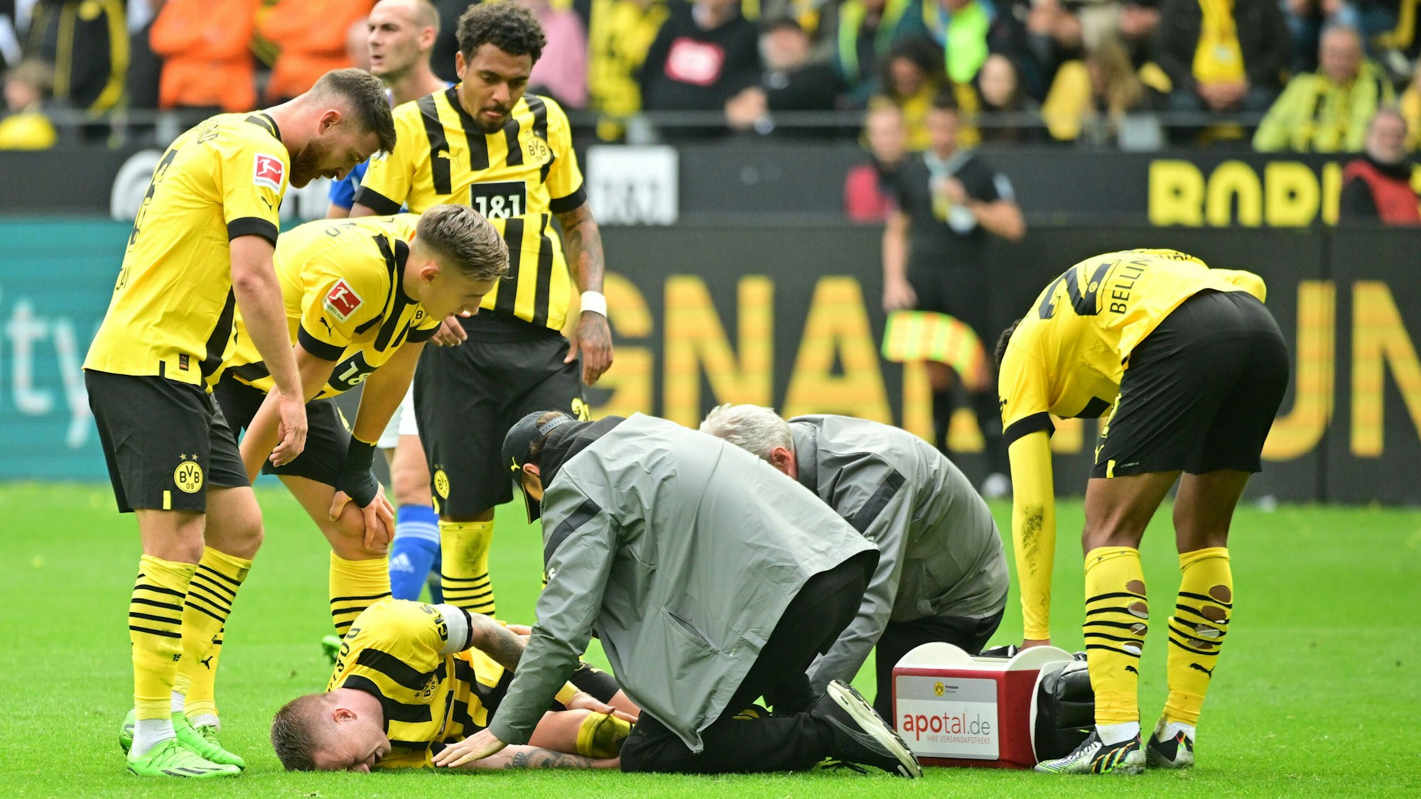 Marco Reus liegt auf dem Rasen und wird vom medizinischen Personal versorgt.