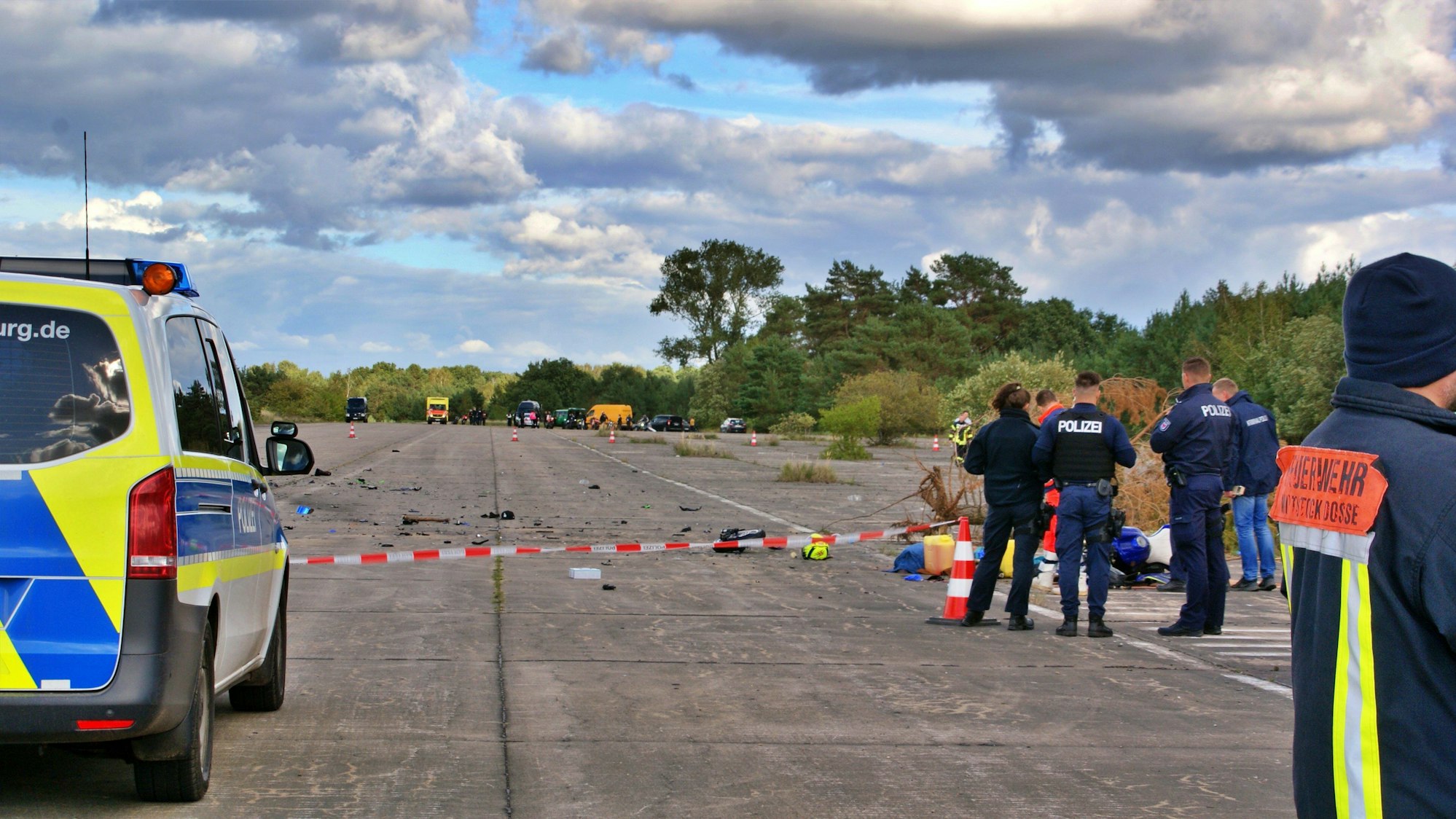 Einsatzkräfte der Polizei und Feuerwehr stehen auf einer alten Flugzeuglandebahn eines ehemaligen Militärflugplatzes. Hier sind am Samstag bei einem Biker-Treffen drei Männer auf zwei Motorrädern ums Leben gekommen.