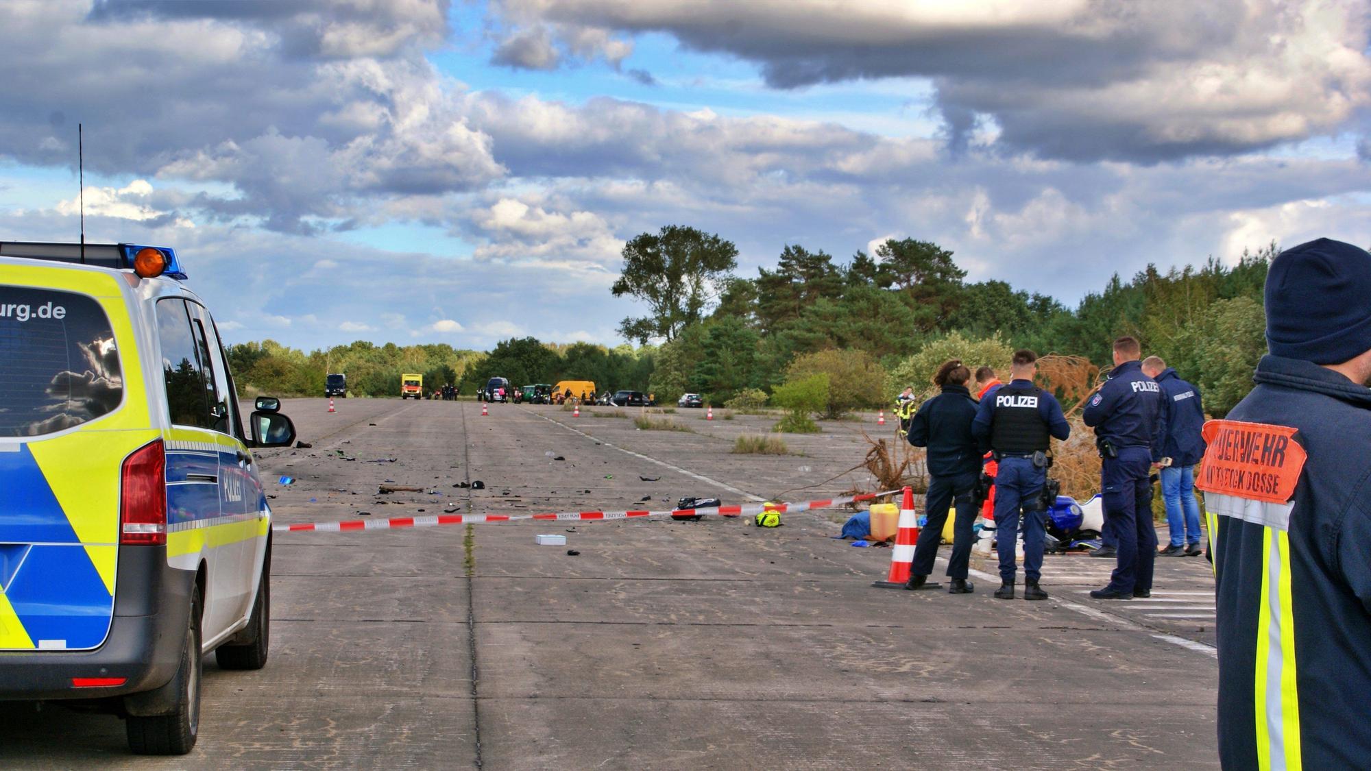 Einsatzkräfte der Polizei und Feuerwehr stehen auf einer alten Flugzeuglandebahn eines ehemaligen Militärflugplatzes. Hier sind am Samstag bei einem Biker-Treffen drei Männer auf zwei Motorrädern ums Leben gekommen.