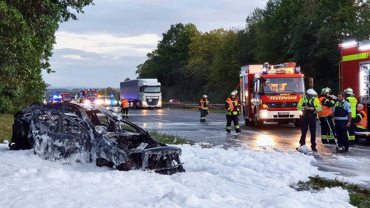 Das nach dem Unfall völlig ausgebrannte Autowrack steht noch in einem See aus Löschschaum neben der Autobahn A1.