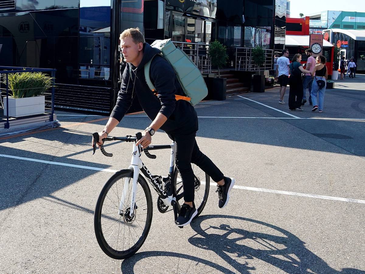Mick Schumacher aus Deutschland von Team Haas fährt steigt im Fahrerlager von einem Fahrrad.
