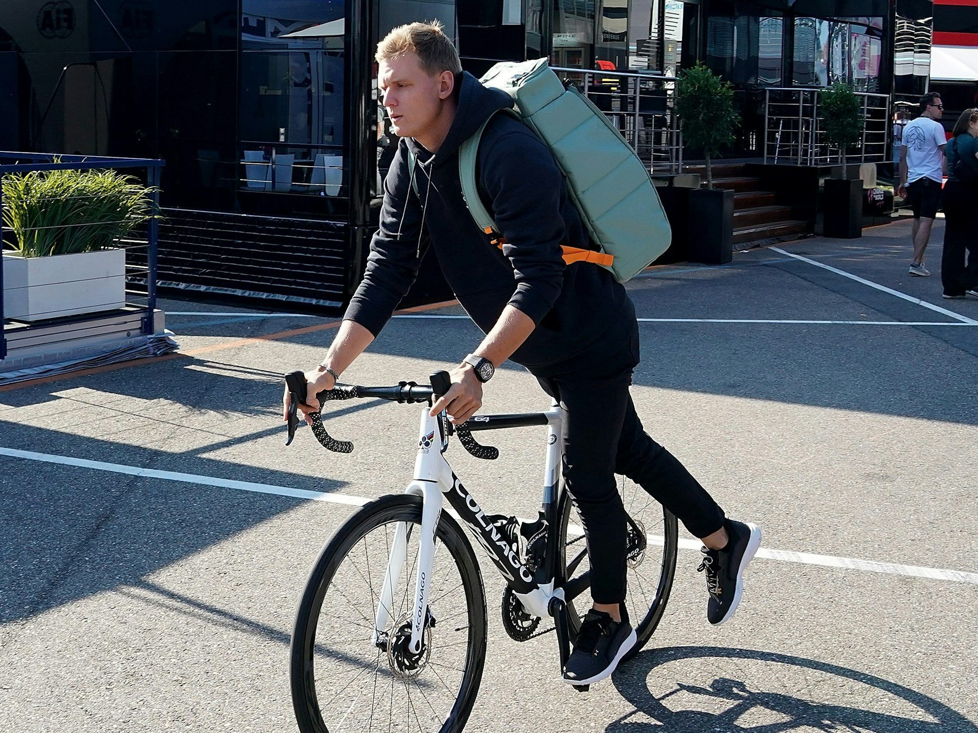 Mick Schumacher aus Deutschland von Team Haas fährt steigt im Fahrerlager von einem Fahrrad.
