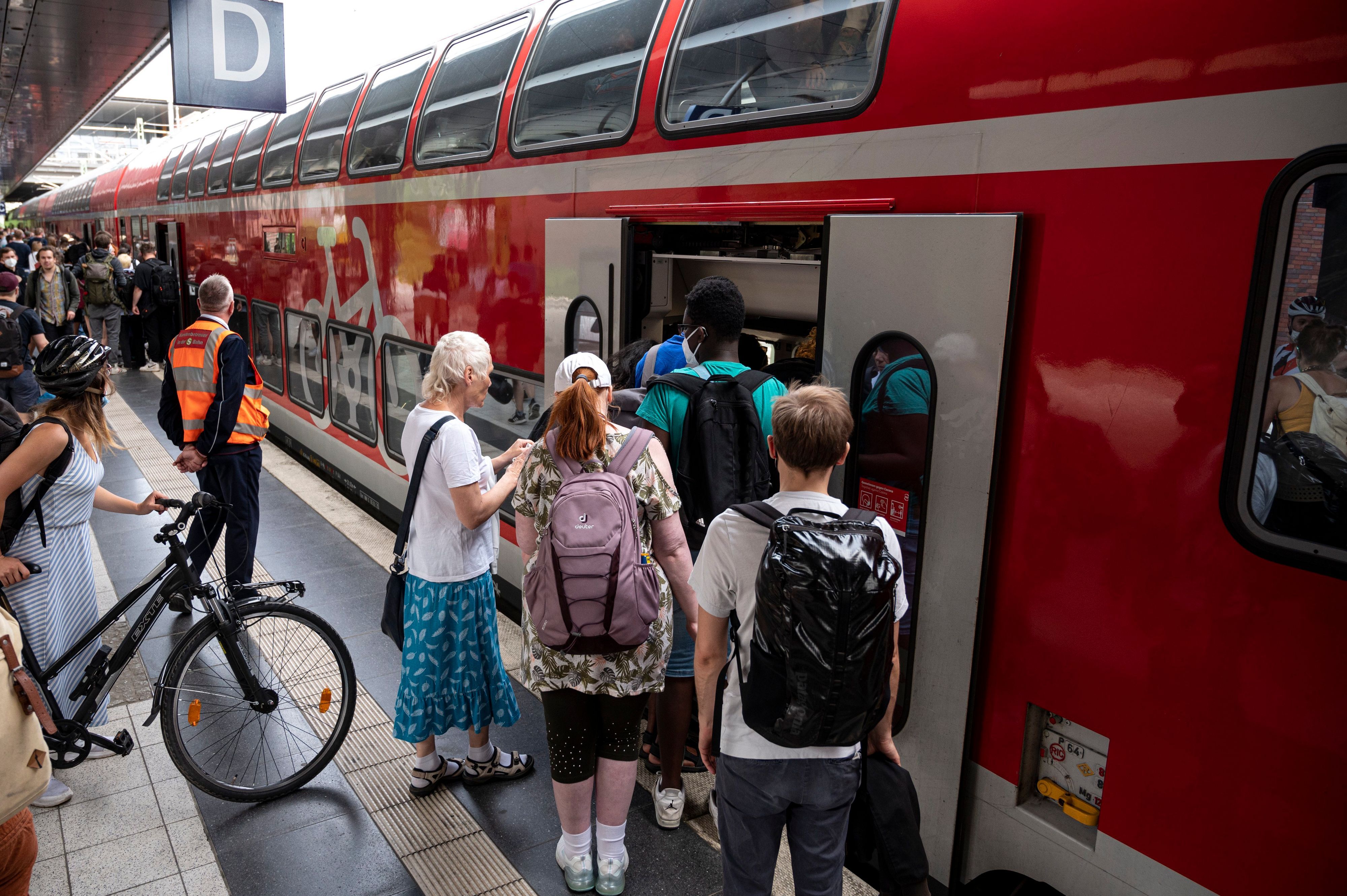 Menschen steigen am Bahnsteig in einen Regionalexpress ein.