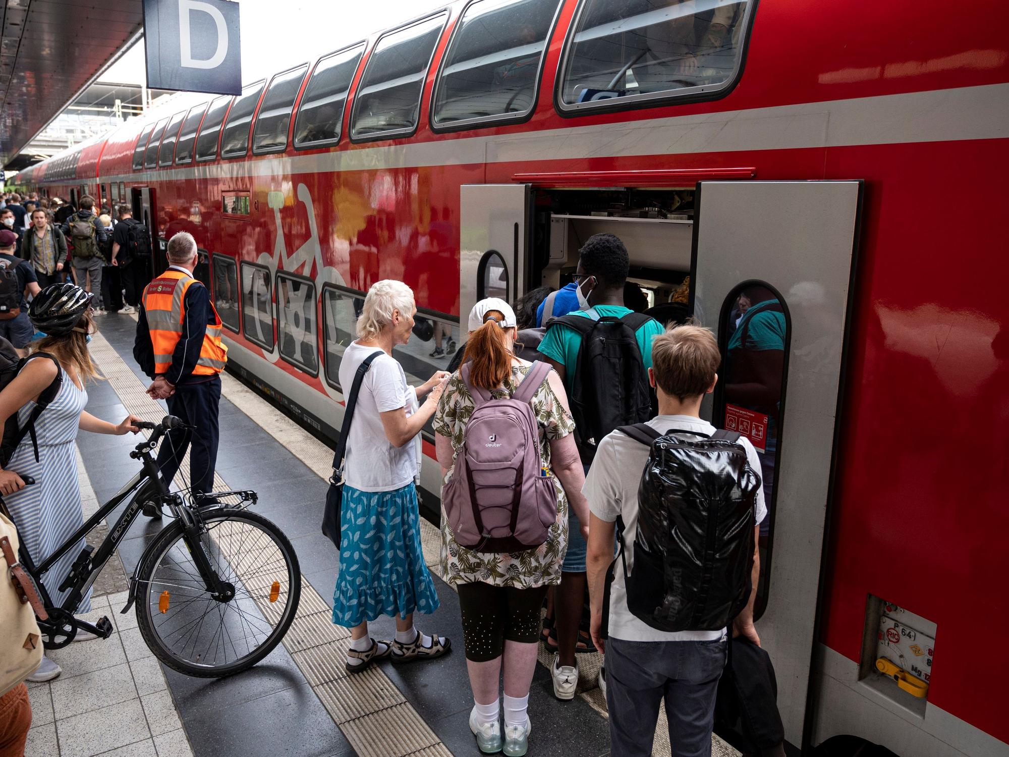 Menschen steigen am Bahnsteig in einen Regionalexpress ein.